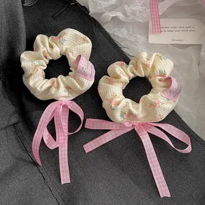 Detailansicht von Blumen-Scrunchies mit rosa karierten Schleifen und Seidenstoff