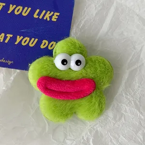 Détail d'une pince à cheveux fleur en peluche verte avec grands yeux et texture douce