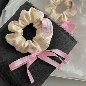 Detailansicht von Blumen-Haargummis mit rosa karierten Schleifen und Blütendesign