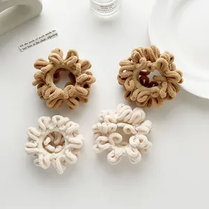 Set of 4 plush hair scrunchies in khaki and cream colors on a minimalist white desk