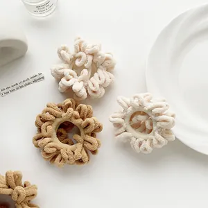 Detailed shot of plush chenille scrunchies in cream and khaki with spiral curly design