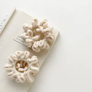 Close-up of cream plush scrunchies with pleated texture on an open English book
