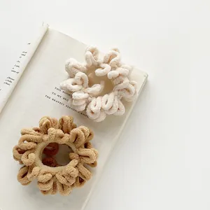 Detail of cream and brown plush scrunchies in soft chenille fabric on an open book