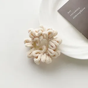 Detailed close-up of cream-colored plush scrunchie showing soft fleece texture and pleats