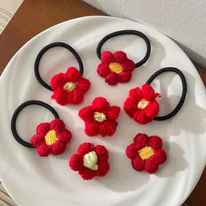 Ensemble d'élastiques et pinces à cheveux en fleurs tricotées rouges sur céramique