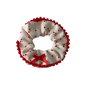 Plush cherry print scrunchie with red pom-pom lace and bow for winter hair styling