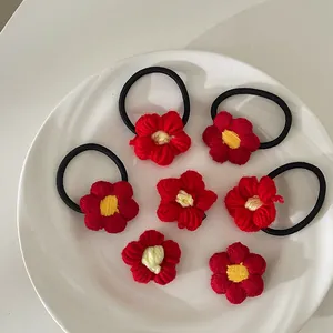 Vue détaillée d'un ensemble de 7 fleurs en tricot rouge faites à la main avec pinces et élastiques