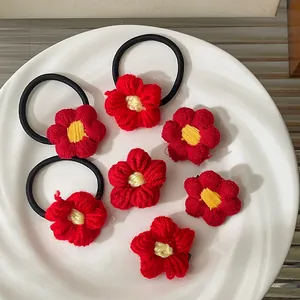 Ensemble d'accessoires de cheveux avec fleurs tricotées rouges sur une assiette blanche