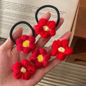 Gros plan de cinq élastiques et pinces à cheveux faits main en fleurs de crochet rouges