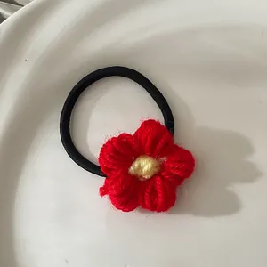 Vue macro de l'élastique à cheveux fleur rouge tricoté à la main avec texture de fil doux