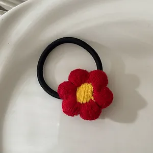 Vue détaillée d'un élastique à cheveux en fleur au crochet avec pétales rouges et jaune
