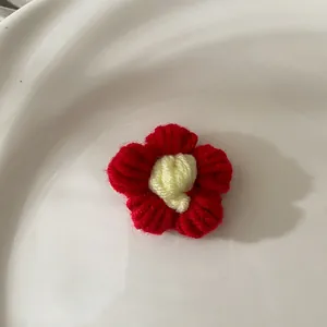 Gros plan sur une fleur au crochet rouge faite main pour cheveux sur céramique blanche