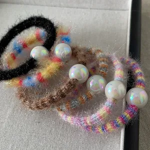 Vue détaillée d'élastiques à cheveux pelucheux avec perles dans une boîte grise
