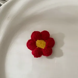 Gros plan d'une fleur rouge tricotée à la main avec un centre jaune dans un bol blanc