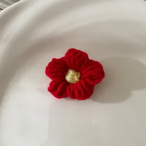 Gros plan d'une fleur rouge crochetée à la main avec centre jaune sur céramique
