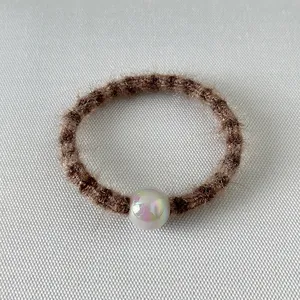 Détail d'un chouchou en peluche marron orné d'une grande perle irisée brillante