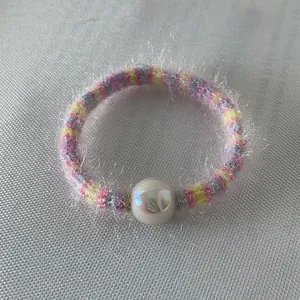 Détail de l'élastique à cheveux rayé arc-en-ciel avec une grande perle blanche nacrée