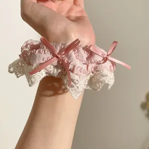 Detail van roze kant haarelastiekje met zijden strikjes om de pols als haaraccessoire
