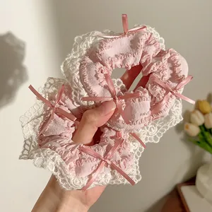 Roze scrunchies met kant en satijnen strikjes vastgehouden door een model