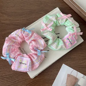 Pink and green plaid scrunchies with bowknots and handmade fabric label on white book
