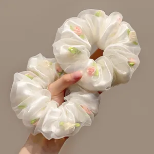Détail de chouchous en tulle ivoire avec broderie de roses roses et motifs de feuilles