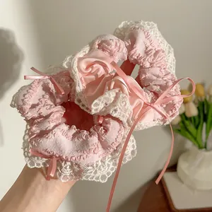 Detail van roze kant haarelastiekjes met satijnen linten en strikken in de hand