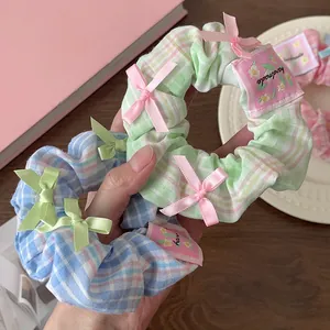 Close-up of handmade plaid scrunchies with cute ribbon bows and floral fabric tags