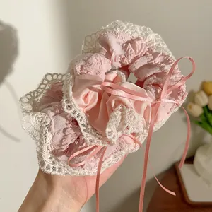 Detail van roze scrunchie met witte kant en lint in een zachte binnenhuisomgeving