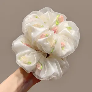 Détails de chouchous en tulle blanc ornés de délicates roses en ruban de satin