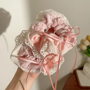 Detail van roze kant haarelastiekjes met lange linten en fijne satijnen plooistof