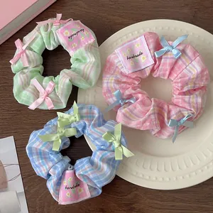 Three-piece plaid scrunchie set with bow detail and handmade labels in blue, green, and pink