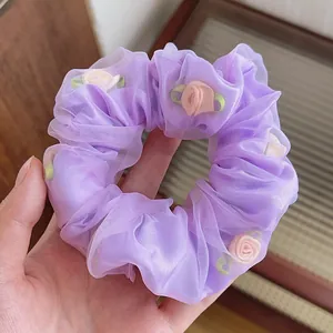 Détail de chouchou en mesh violet avec appliques de roses roses 3D et feuilles vertes