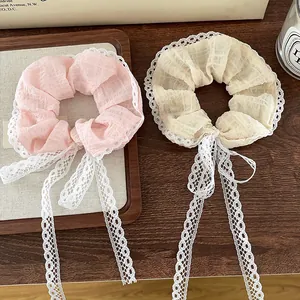 Detailed view of pink and beige lace scrunchies with long ribbons on a wooden tray