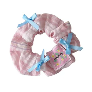 Pink checkered scrunchie with blue bows and handmade label for elegant hair styling
