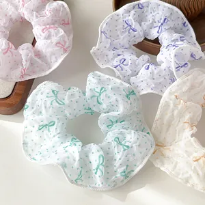 Nahaufnahme von gefalteten Organza-Haargummis mit Punkten und Schleifenmustern in Pastell