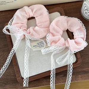 Set of two pink scrunchies with white lace ribbons on a vintage wooden tray