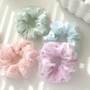 Dettaglio di quattro scrunchies in organza floreale in colori pastello e ombre soffuse