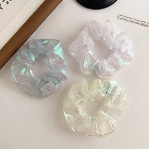 Detailed view of iridescent organza LED scrunchies in blue, pink, and yellow colors