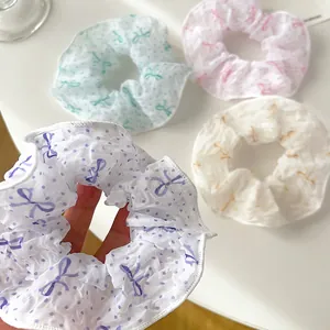 Detail von vier bunten Haargummis mit Punkten und Schleifen in Lila, Grün, Rosa und Cremeweiß