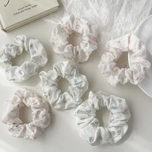 Set of 6 floral scrunchies with pink and blue patterns on white fabric in a stylish setup