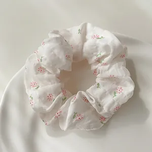 Close-up of floral scrunchie with pink daisies on a wavy white ceramic tray