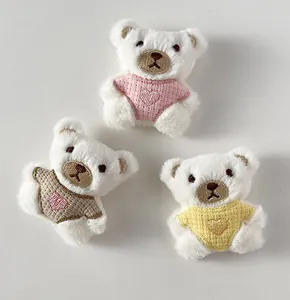 Dettaglio di tre piccoli orsetti di peluche in rosa, giallo e kaki per lavori manuali