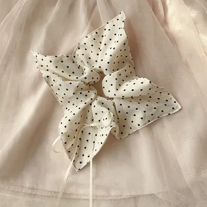 Dettaglio dell'elastico crema a pois con fiocco su uno sfondo di tulle morbido