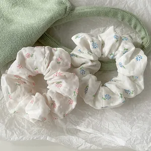Detailed view of floral scrunchies in pink and blue chiffon with soft pleat textures