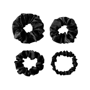 Detailed set of four black satin silk scrunchies in various sizes on white background