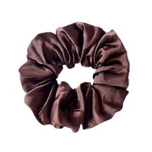 Close-up of a dark brown satin scrunchie with smooth silk texture and glossy finish