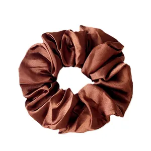 Detail shot of a coffee brown satin scrunchie with a glossy silk texture and rich folds