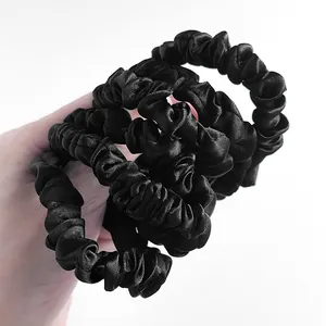 Detailopname van zwarte satijnen scrunchies met zijden textuur en geplooid ontwerp