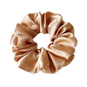 Detail shot of oversized satin champagne gold scrunchie with silky pleated texture