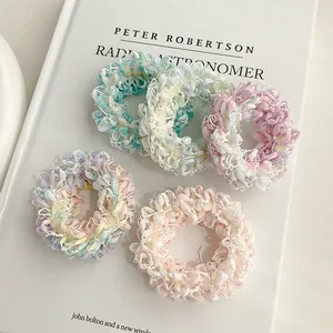 Détail de cinq chouchous en tricot colorés à texture douce posés sur un livre